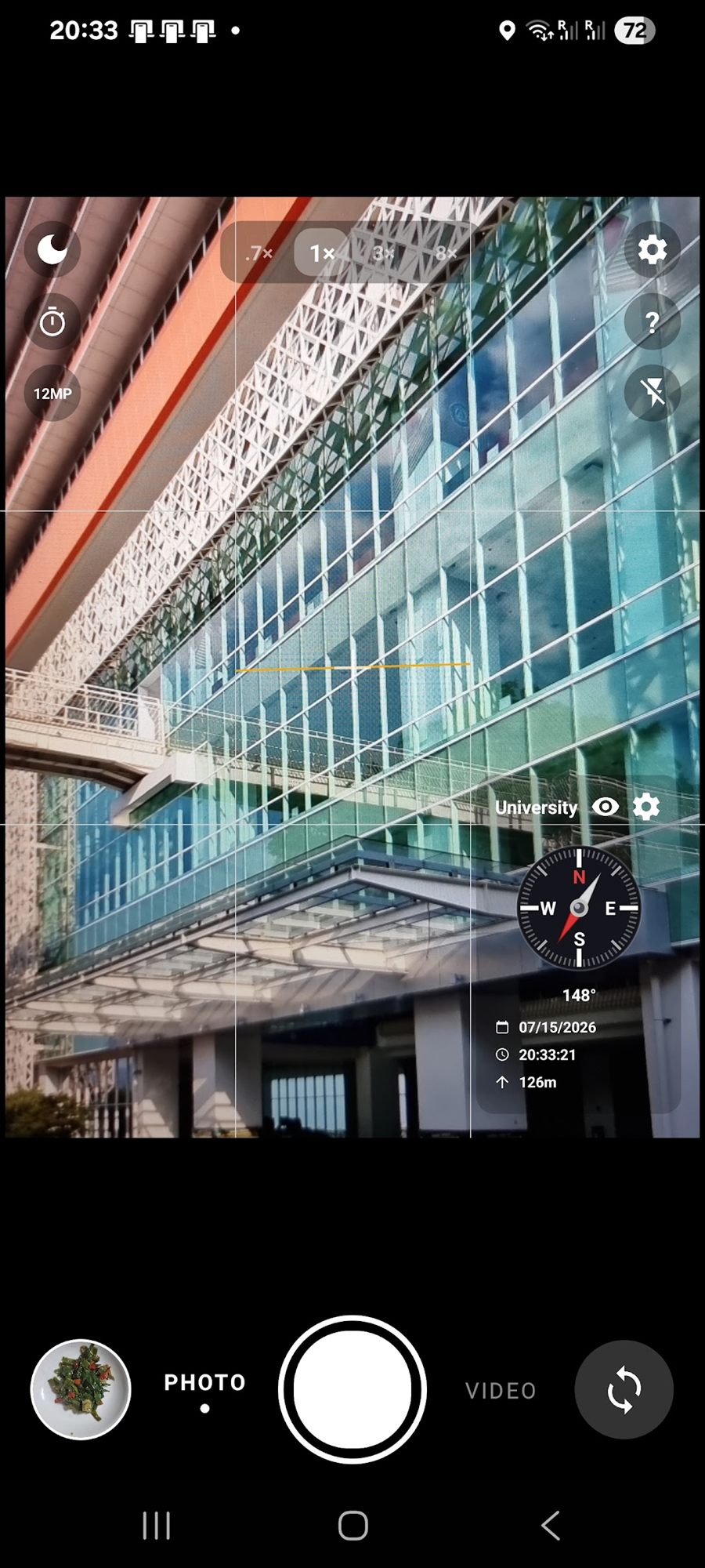 The MemoCam viewfinder showing a glass building, with a compass reading 148 degrees, the date, the time and 126 m altitude in the corner.